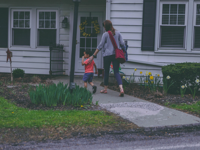 woman and kid entering to their house with patio and some flowers